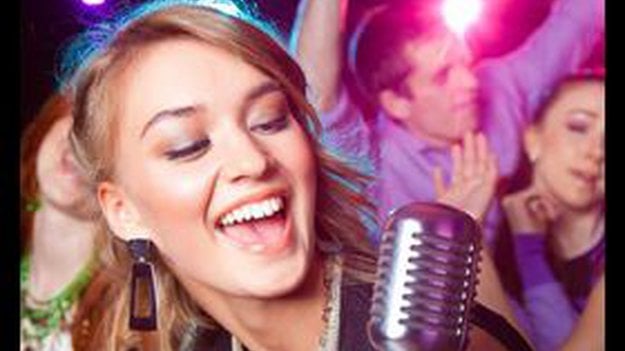 Frau singt in ein Karaoke Mikrofon