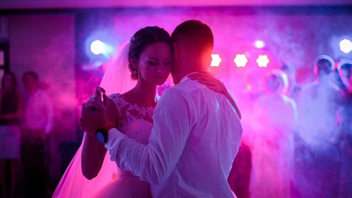 Ein DJ hat gerade einen Hochzeitswalzer in Düsseldorf aufgelegt. Das Brautpaar tanzt in violettem Licht gehüllt.